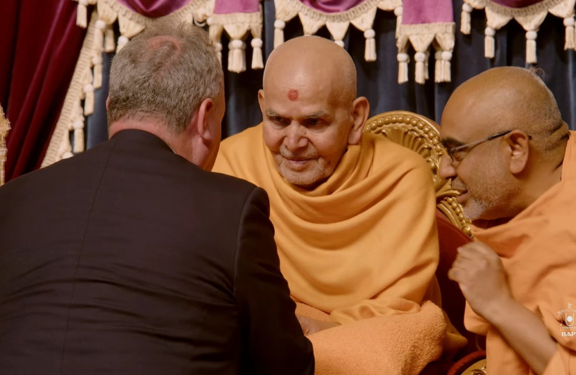 Bob Blackman receiving blessing on stage by Mahant Swami